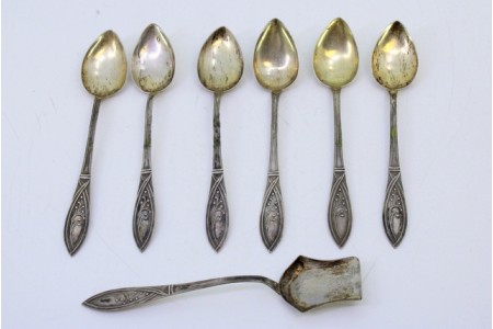 Conjunto de seis colheres de café e pá de açúcar em prata dourada nas conchas e relevos nos cabos.